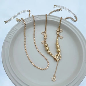Detail of gold star pendant necklace set with toggle clasp on white ceramic tray
