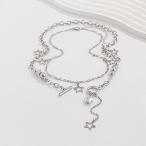 Macro detail of silver-toned layered necklaces with star pendants and toggle clasp