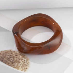 Close-up of chunky irregular amber resin bangle with marble texture and high gloss