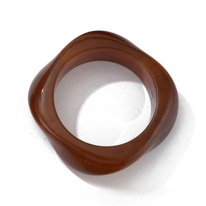 Macro detail of amber resin bangle showing the irregular wavy edge and glossy surface