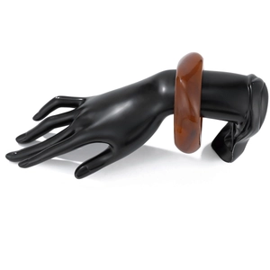 Close-up of translucent amber acrylic wide bangle on a black hand display model