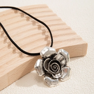 Dettaglio di un ciondolo rosa vintage in argento su una collana a cordino nero