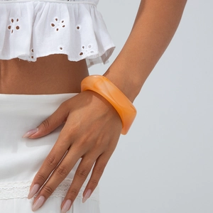 Detail view of translucent orange resin bangle with marble texture on model wrist