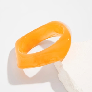 Detail showing irregular translucent orange acrylic bangle with marble texture on white stone