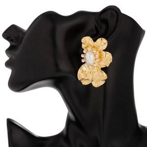 Macro-opname van gouden ginkgo-oorbel met centrale witte parel op een zwarte etalagepop