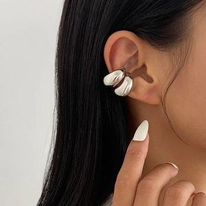 Gros plan d'un ear cuff argenté géométrique en forme de C avec finition polie sur l'oreille