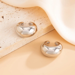Détail macro de boucles d'oreilles créoles épaisses en argent poli sur pierre texturée