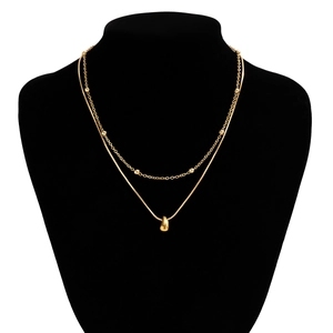 Détail d'un collier double rang doré avec pendentif goutte sur un buste de velours