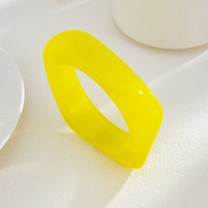 Detailed close-up of chunky translucent yellow acrylic geometric bangle on white background