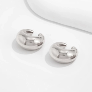 Détail macro de boucles d'oreilles en métal argenté poli avec finition brillante miroir