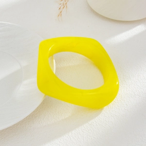Detail of translucent yellow acrylic geometric bracelet on minimalist background