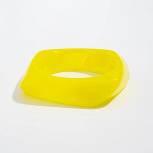 Close-up of a wide square acrylic bracelet in translucent bright yellow with glossy finish