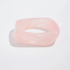 Close-up of a wide chunky pink resin bangle with white marble texture and glossy finish