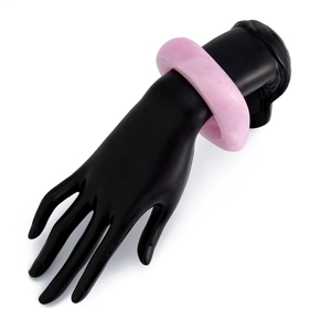 Detail of pink marble textured acrylic wide bangle on a black display hand model