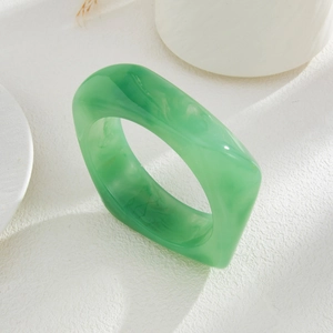 Close-up of a chunky dark green marbled acrylic square bracelet on a white textured background