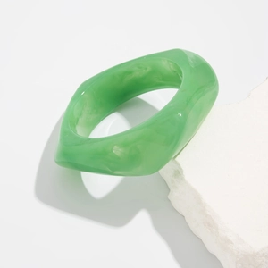 Detail of light green irregular resin bangle with marble texture on white stone