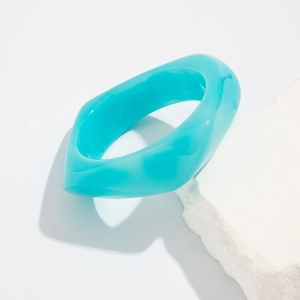 Detail of teal translucent acrylic bangle with irregular geometric design on stone