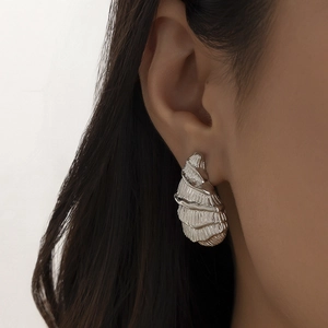 Detailed close-up of silver punk style teardrop earrings with textured spiral layers