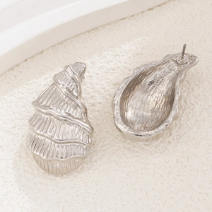 Detailed close-up of silver conch shell earrings with refined striped texture and pin back