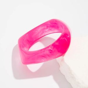 Macro view of wide translucent magenta acrylic bangle with marble texture and irregular shape
