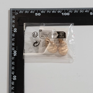 Detailed view of golden teardrop earrings with textured ridges measured on a scale