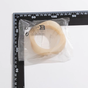 Close-up of translucent cream irregular bangle in fashion packaging with size scale