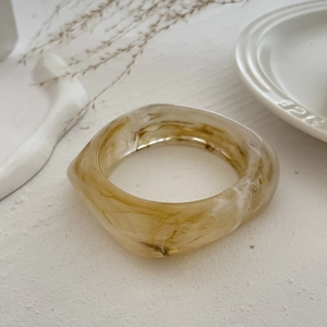 Macro detail of amber marbled resin bangle with smooth edges and chunky minimalist design