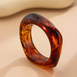 Macro detail of amber resin bangle with red-brown tortoiseshell pattern and glossy finish