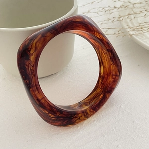 Detail of amber tortoiseshell acrylic bangle with irregular geometric resin texture