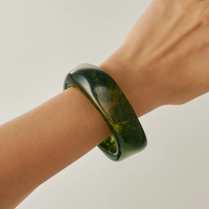 Close-up of translucent dark green resin bangle with marble texture on female wrist