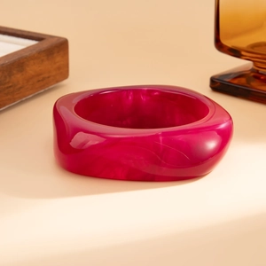 Close-up of chunky translucent rose red resin bangle with geometric cloud texture