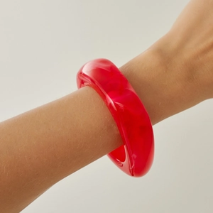 Close-up of chunky translucent red acrylic bangle with marble texture on wrist