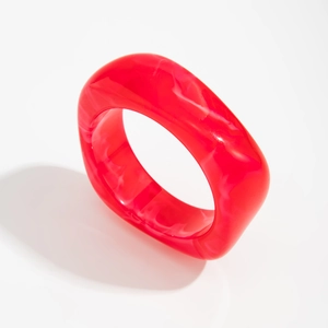 Close-up of a chunky red translucent acrylic bracelet with marbled resin texture