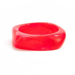 Macro detail of a red translucent acrylic bangle with an irregular geometric design