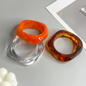 Irregular translucent acrylic resin bangles in amber, orange, and clear finish