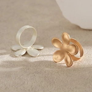 Detailed close-up of gold and silver floral rings with matte finish on textured stone
