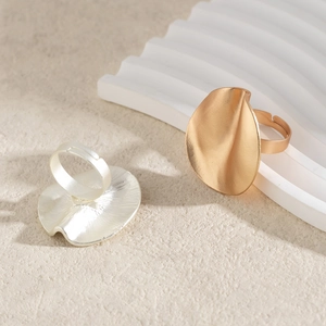 Detailed close-up of gold and silver irregular wavy disc rings with matte metal texture