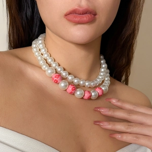 Detail einer zweilagigen Kunstperlenkette mit rosa Perlen und roten Lippenmotiven