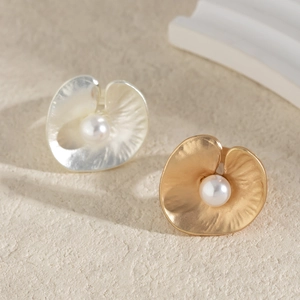 Detail of irregular gold and silver leaf rings with pearls on stone background