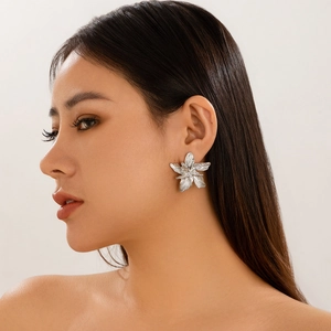 Detail of large silver floral earrings with brushed texture worn by a female model