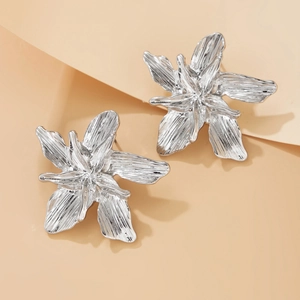 Macro detail of silver lily flower earrings with refined metallic brushed textures