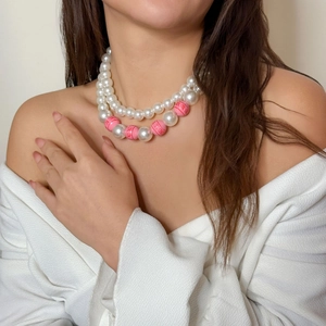 Nahaufnahme der zweilagigen Perlenkette mit rosa XOXO-Perlen am Hals des Models