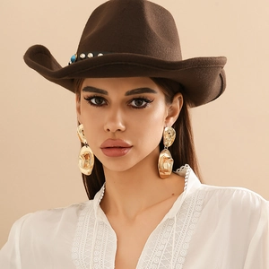 Close-up of stylish gold cowboy hat earrings worn by a model with a felt hat and lace top