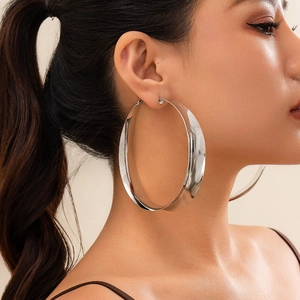 Nahaufnahme von großen silbernen Creolen mit Hochglanz-Finish für Damen im modernen Stil