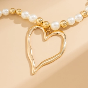 Detail of irregular hollow gold heart pendant with white faux pearls and gold beads