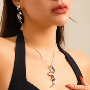 Detalle del conjunto de collar y pendientes de metal líquido retorcido en modelo