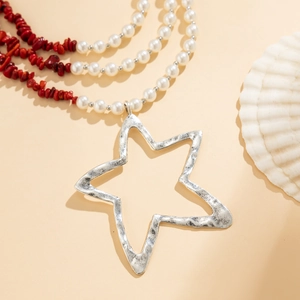 Detail van de gelaagde parelketting met een gehamerde zilveren stervormige hanger