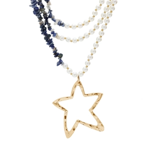 Detail van een gelaagde ketting van turkoois en parels met gehamerde sterhanger