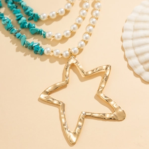 Detail van gelaagde ketting met gouden sterhanger en kralen van turkoois
