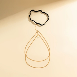 Detailed macro view of gold star pendant on black elastic leg chain with layered tassels